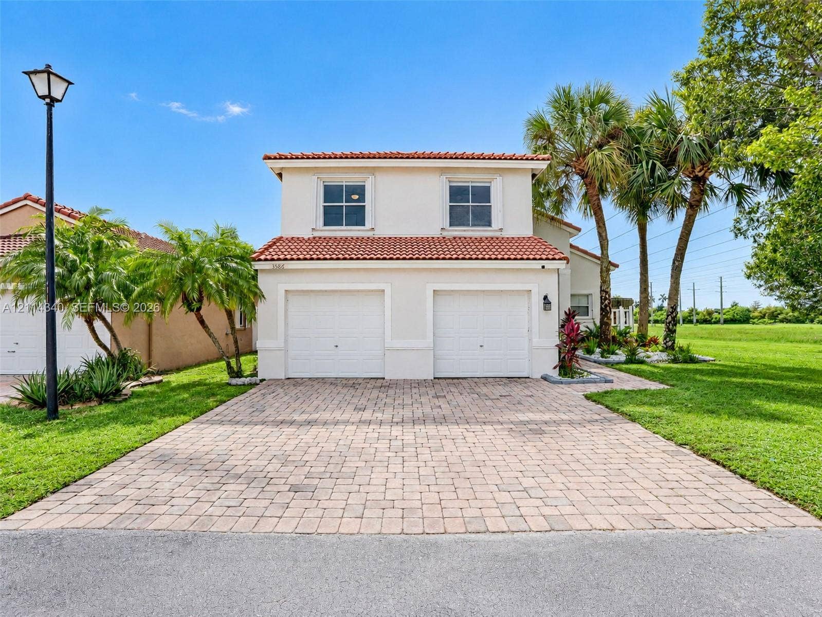 3586 SW 50th Street, Hollywood, FL 33312 Two-story exterior featuring a light stucco facade, terracotta-tiled roof, double-car garage, and a paved brick driveway