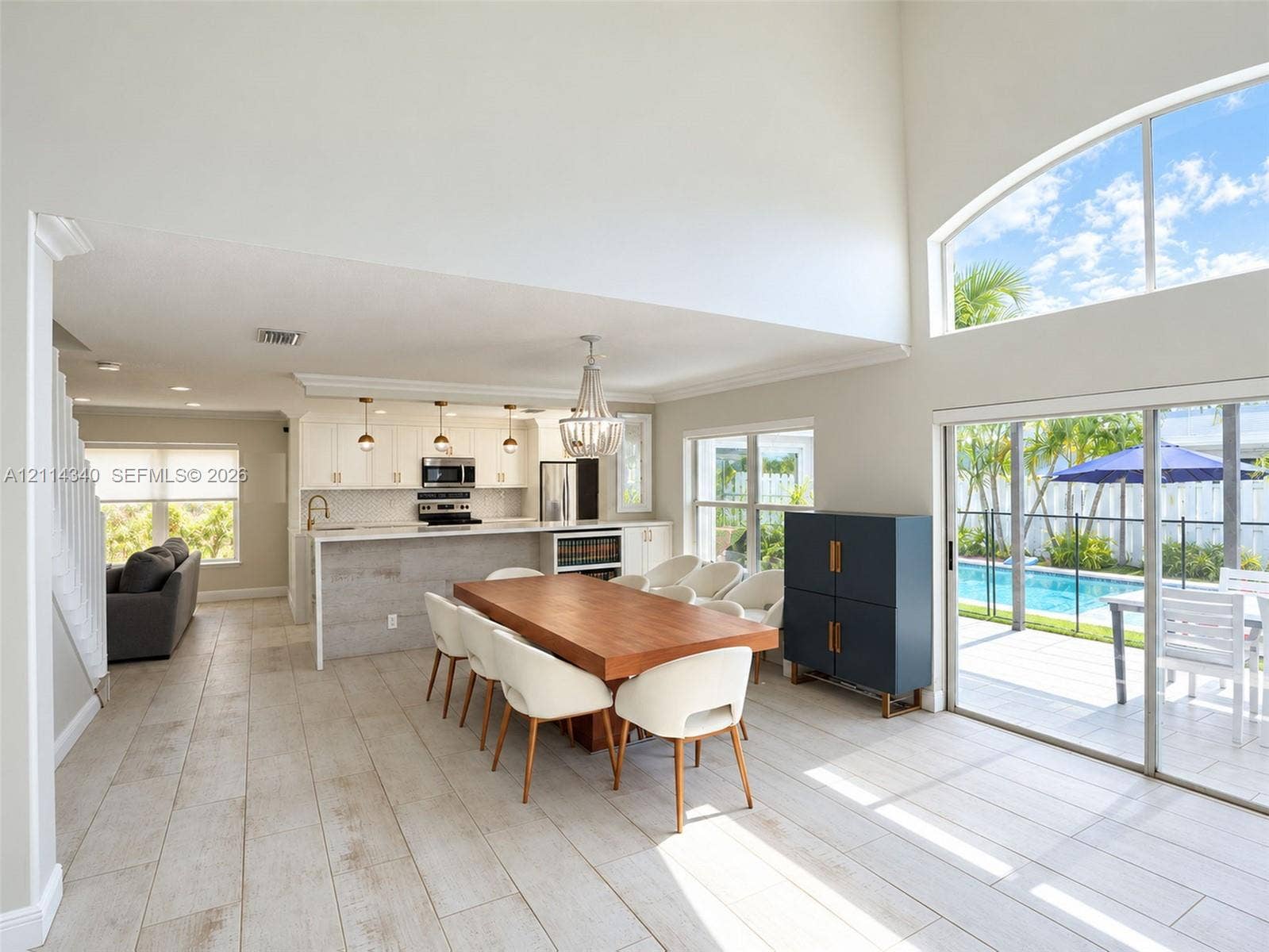 3586 SW 50th Street, Hollywood, FL 33312 Open-concept floor plan featuring high ceilings, wood-finish tile flooring, a chef's kitchen with a stone-top island, and large sliding glass doors providing outdoor access