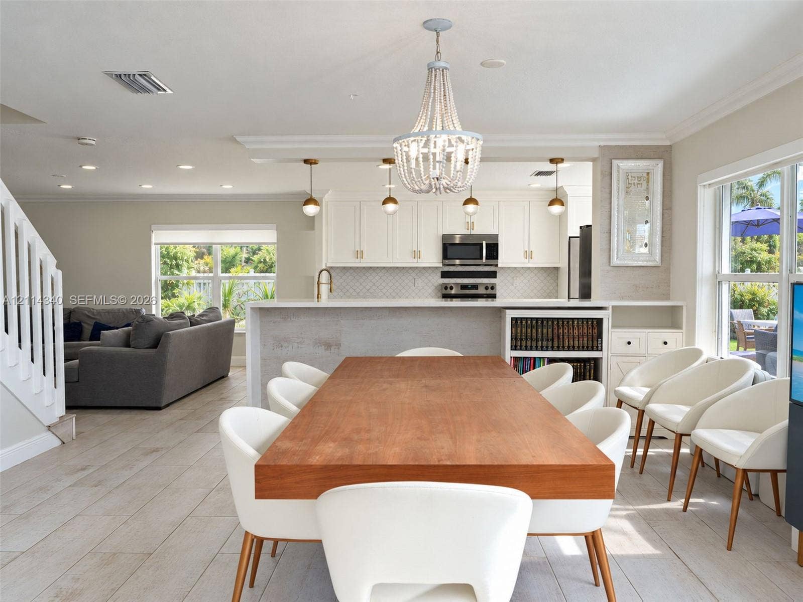 3586 SW 50th Street, Hollywood, FL 33312 Kitchen featuring white shaker-style cabinetry, a quartz countertop island, stone-patterned backsplash, wood-finish flooring, and a decorative bead-frame chandelier