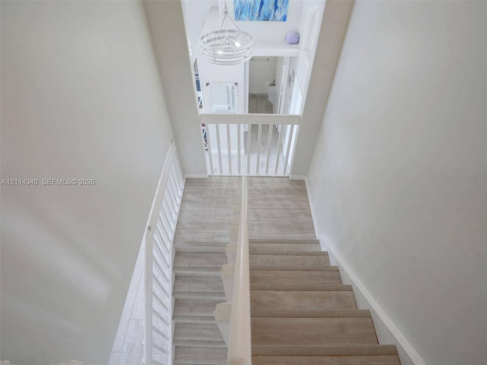 3586 SW 50th Street, Hollywood, FL 33312 Staircase featuring wood-finish treads, white painted balustrades, and a tiered drum chandelier
