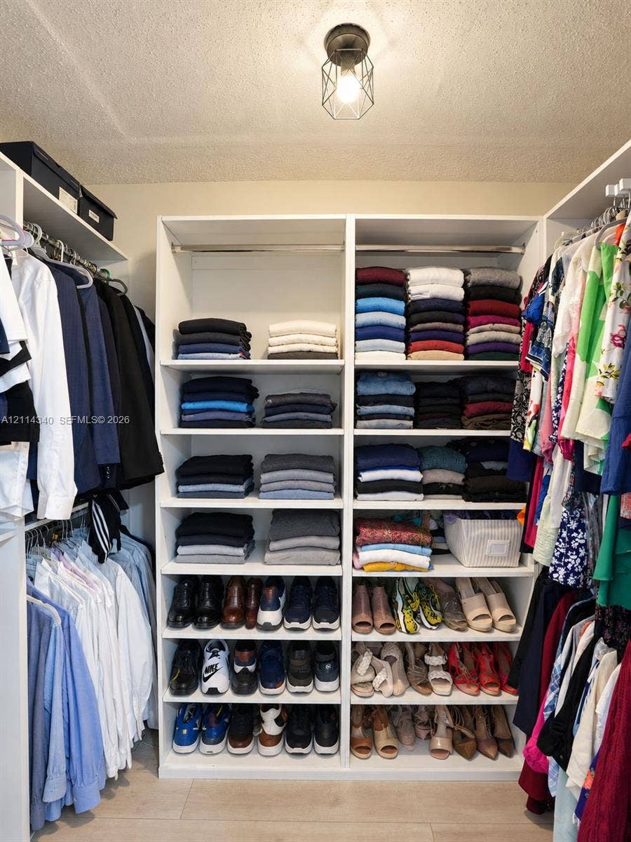 3586 SW 50th Street, Hollywood, FL 33312 Walk-in closet featuring white built-in shelving, multiple hanging rods, and an industrial-style geometric flush mount light fixture