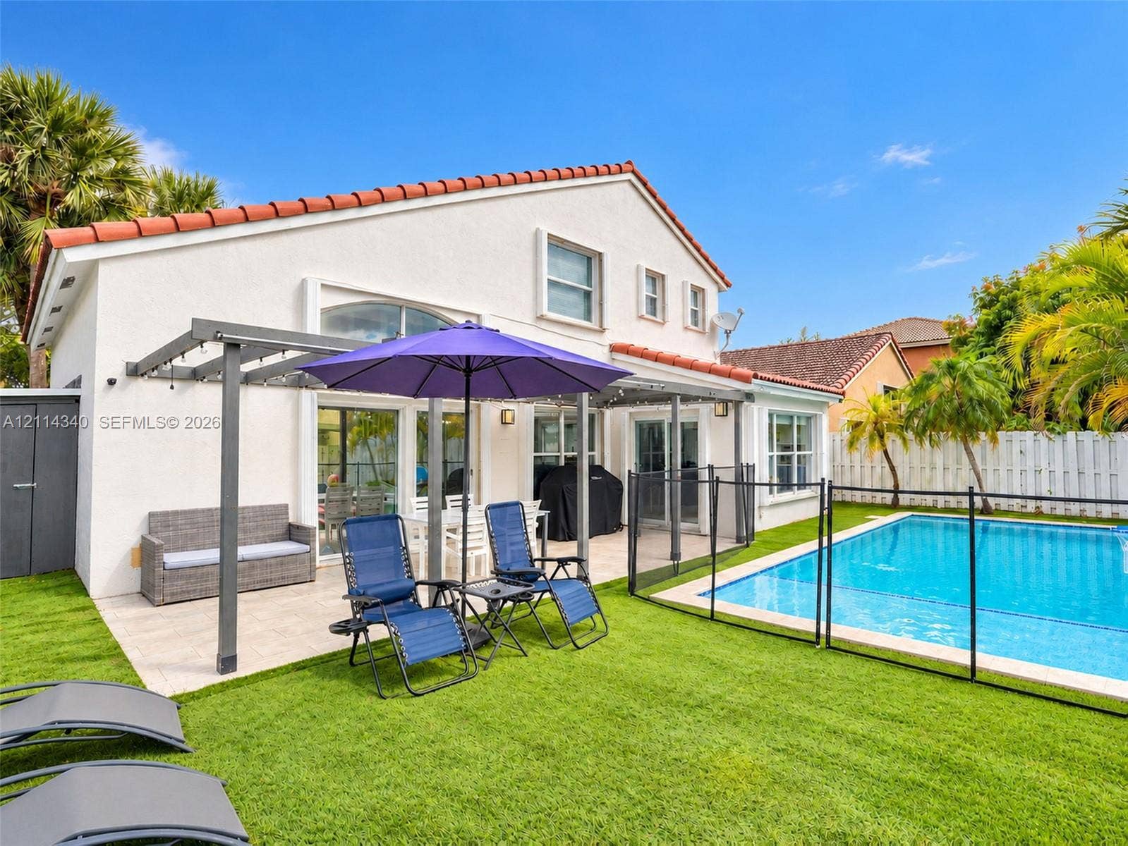 3586 SW 50th Street, Hollywood, FL 33312 Stucco exterior with a tiled roof, featuring a covered patio, swimming pool, and artificial turf lawn