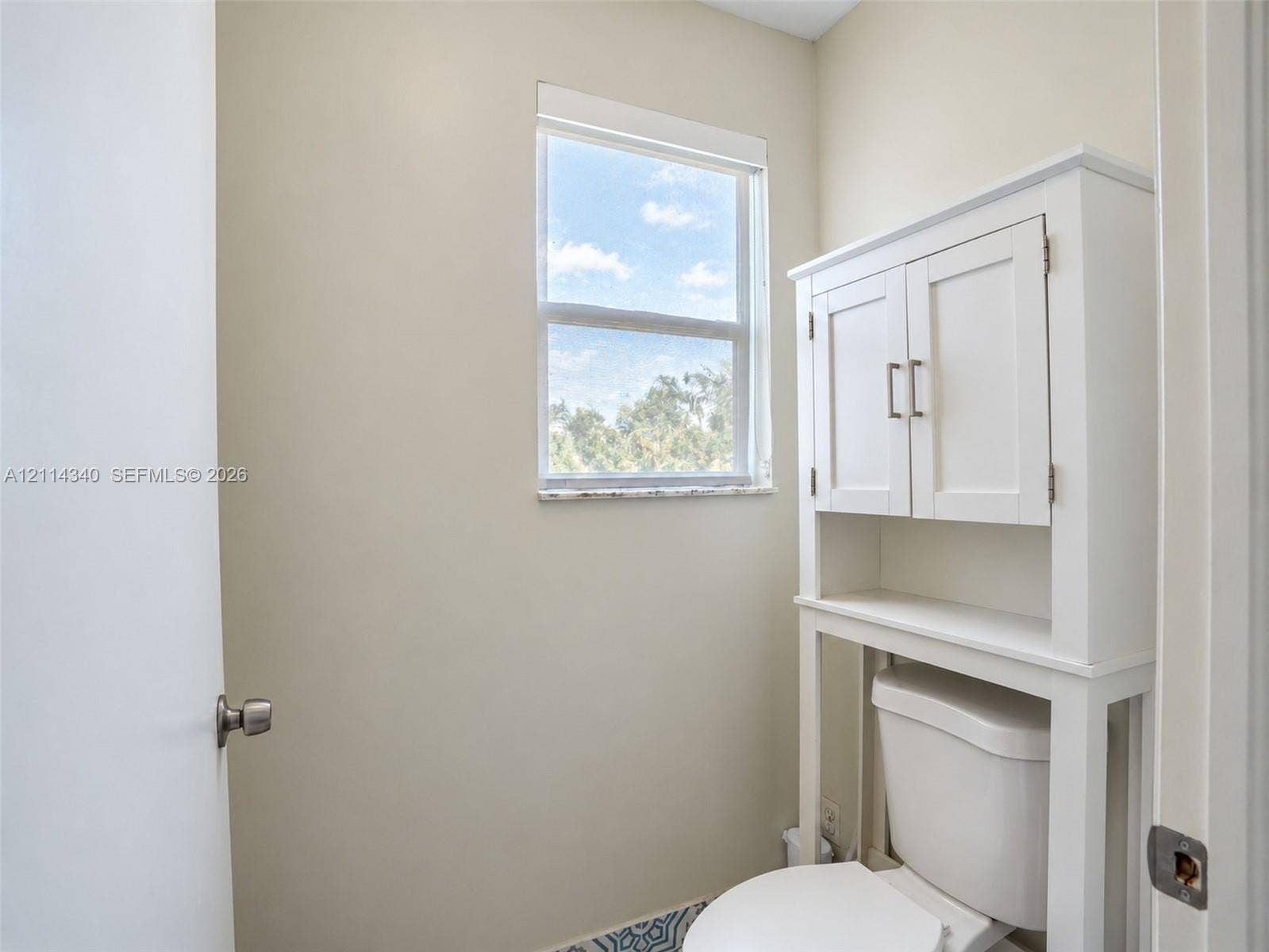 3586 SW 50th Street, Hollywood, FL 33312 Single-pane window with a stone-finish sill, built-in over-the-toilet storage cabinetry, and patterned tile flooring