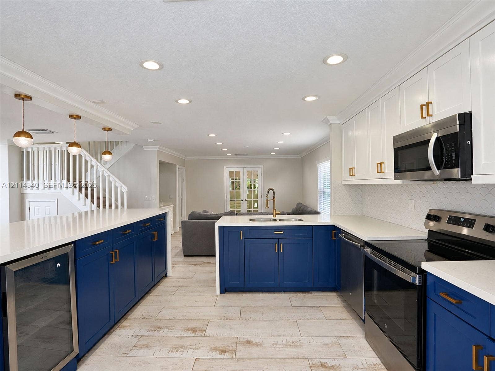 3586 SW 50th Street, Hollywood, FL 33312 Kitchen featuring custom blue and white cabinetry, quartz countertops, scalloped tile backsplash, recessed lighting, and wood-finish tile flooring