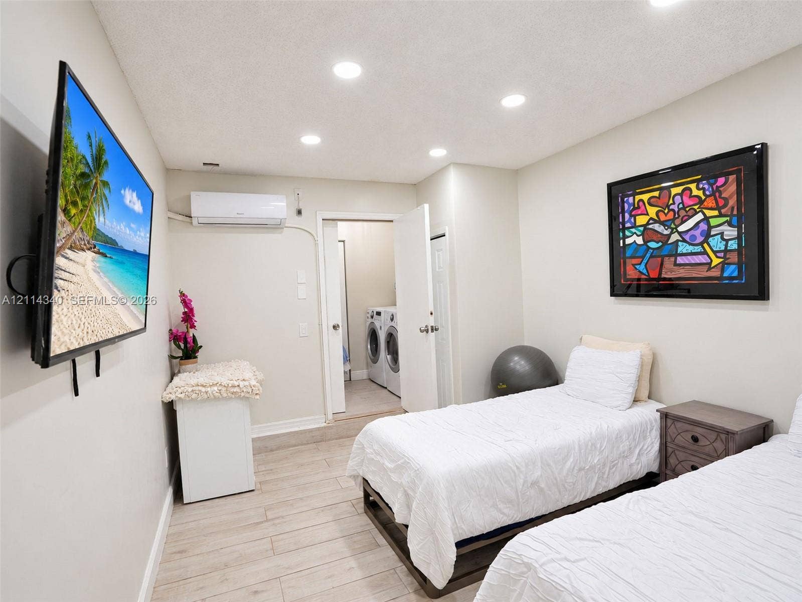 3586 SW 50th Street, Hollywood, FL 33312 Neutral-toned room featuring recessed ceiling lighting, wall-mounted ductless heating and cooling unit, wood-finish flooring, and a dedicated laundry area