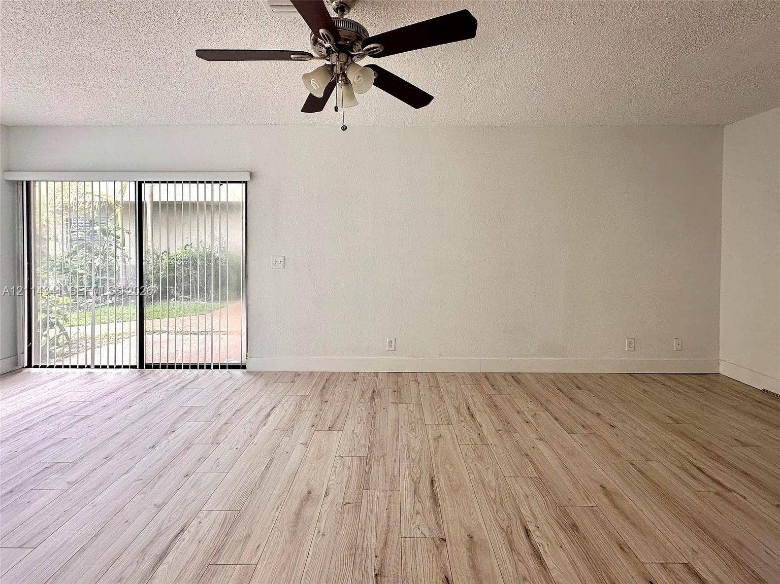 Interior space featuring wood-finish flooring, sliding glass patio doors, and a ceiling-mounted fan with integrated lighting