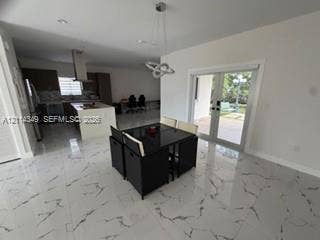 Polished stone-finish tile flooring, kitchen island with built-in cabinetry, stainless steel range hood, recessed lighting, and double glass pane doors