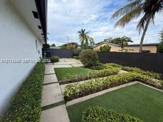 Landscaped backyard featuring tiered turf lawn sections, linear concrete pavers, structured hedge borders, and a privacy fence