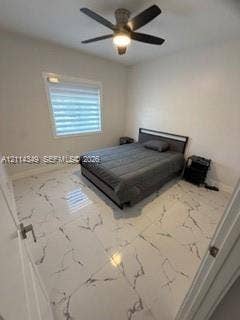 Large-format tile flooring with veined detailing, neutral wall tones, multi-blade ceiling fan with integrated lighting, and horizontal shade window treatment