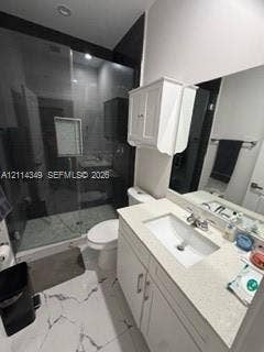 Bathroom featuring a glass-enclosed shower with tile surround, white cabinetry, integrated sink with stone-finish countertop, and large-format porcelain tile flooring