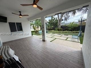 Covered patio featuring wood-finish flooring, recessed ceiling fans, and a large-format paver hardscape with grass inlays
