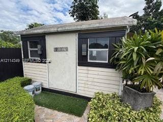 Detached structure featuring horizontal siding, dual windows with black trim, and wall-mounted exterior lighting
