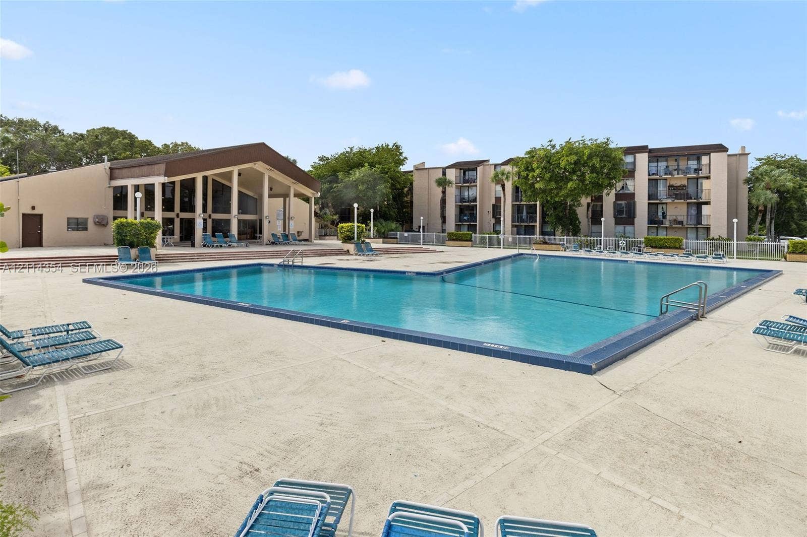14401 SW 88th Street, #410N, Miami, FL 33186 Large swimming pool with a concrete pool deck, encompassing structure with a covered pavilion, and perimeter fencing