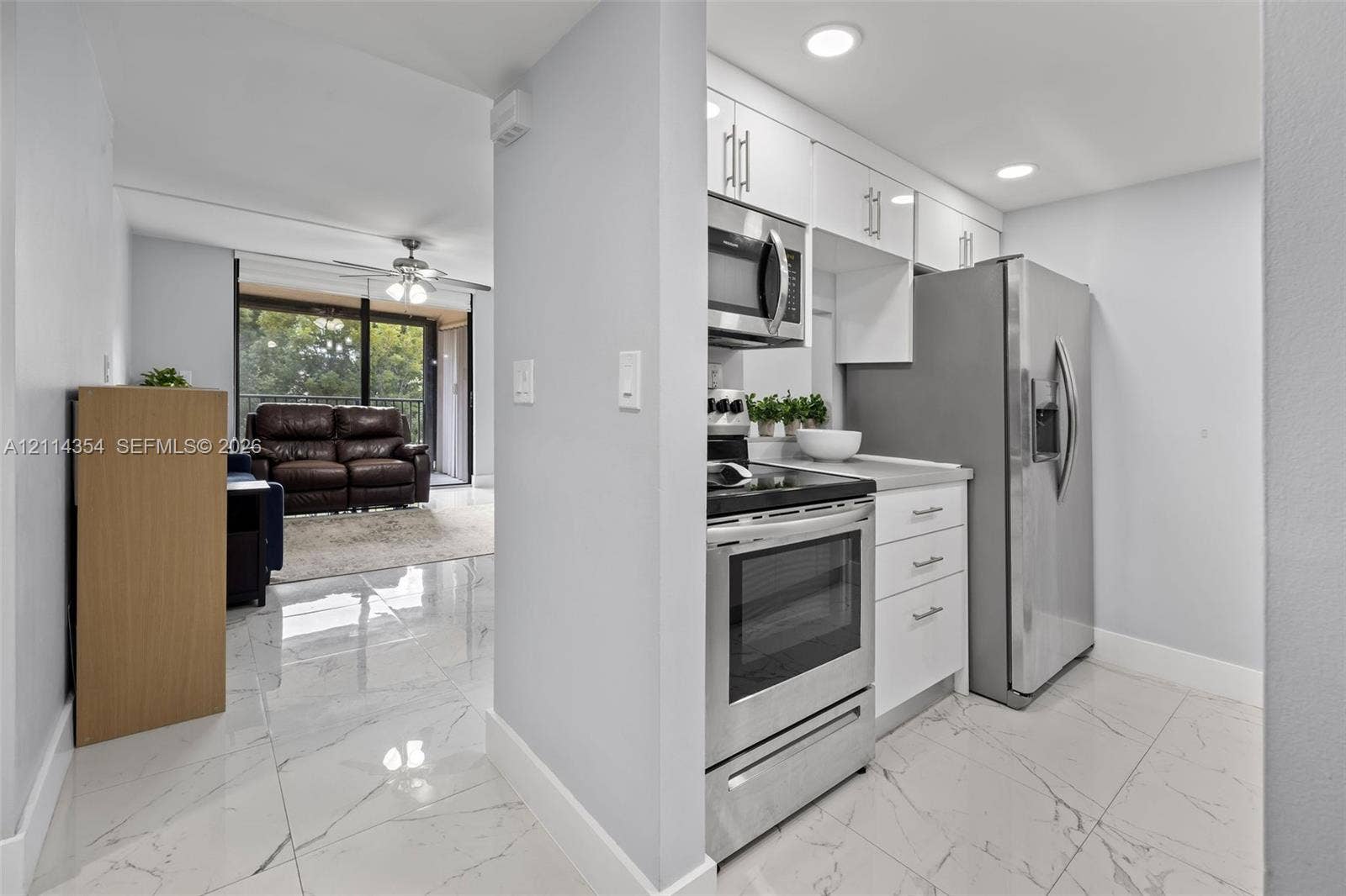 14401 SW 88th Street, #410N, Miami, FL 33186 Kitchen featuring white cabinetry, stainless steel appliances, and solid surface countertops complemented by polished tile flooring with a veined pattern