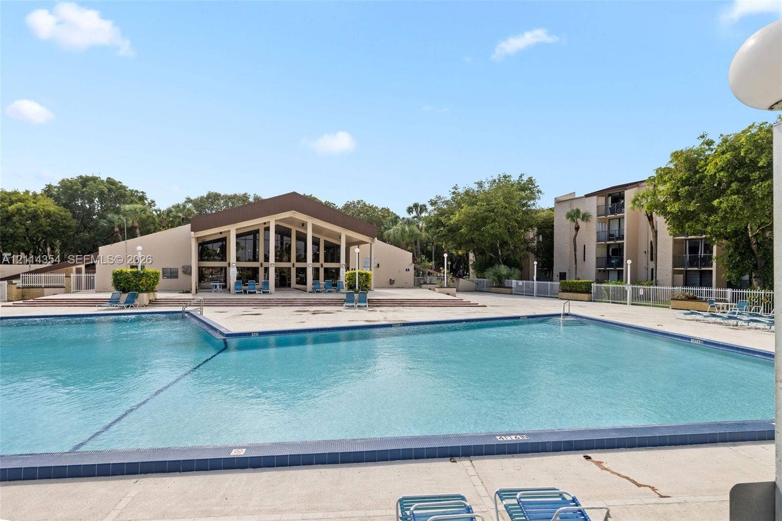 14401 SW 88th Street, #410N, Miami, FL 33186 Swimming pool with tiled coping, surrounding concrete deck, and multi-story building exterior