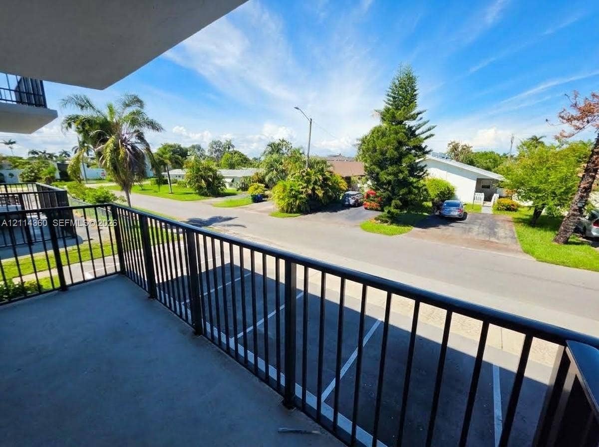 Covered balcony featuring black metal railings and concrete flooring