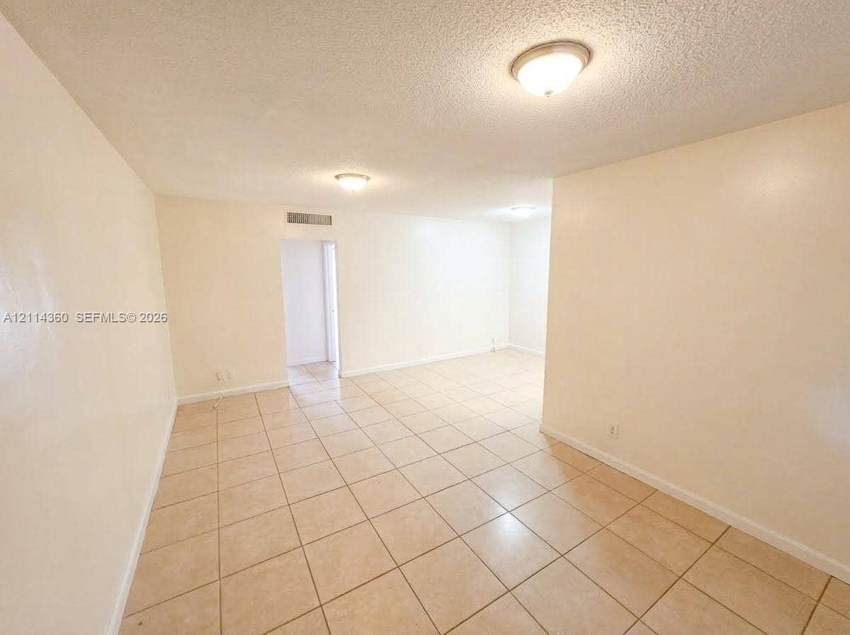 Neutral-toned ceramic tile flooring, textured ceilings, and flush-mount lighting fixtures