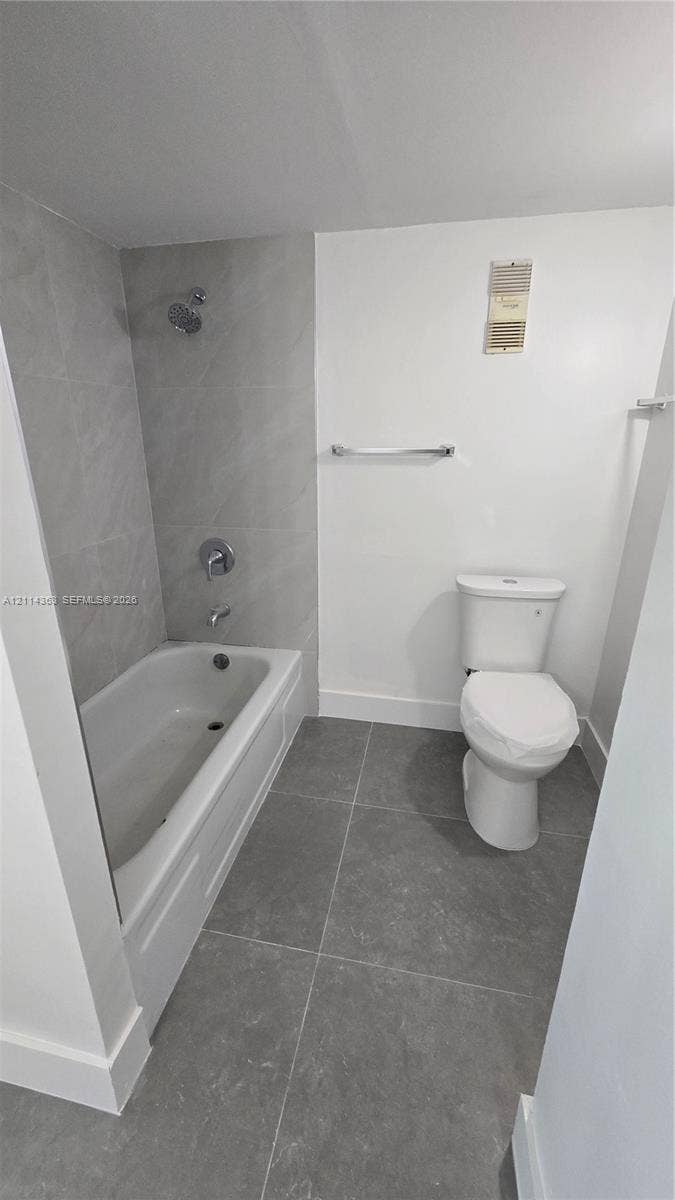 14840 Naranja Lakes Boulevard, #1G, Homestead, FL 33032 Full bathroom featuring large-format grey tile flooring, a bathtub with a matching grey tile surround, and a wall-mounted chrome towel bar