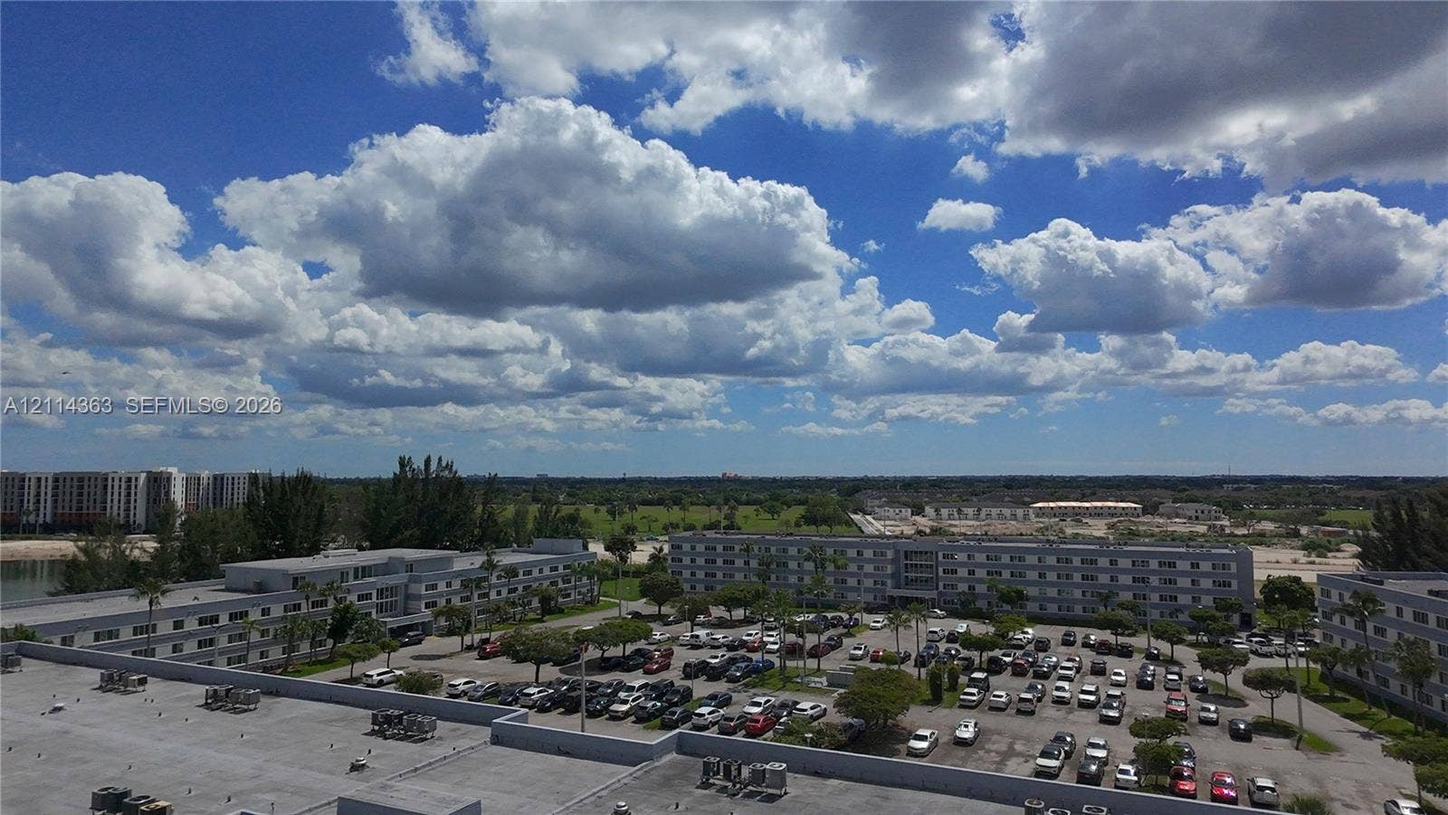 14840 Naranja Lakes Boulevard, #1G, Homestead, FL 33032 Aerial perspective featuring multi-story residential buildings, paved surface parking lots, and landscaped grounds with mature palm trees