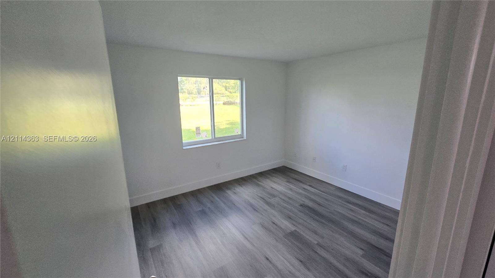14840 Naranja Lakes Boulevard, #1G, Homestead, FL 33032 Interior space featuring wood-finish flooring, white walls, and a single-pane sliding window
