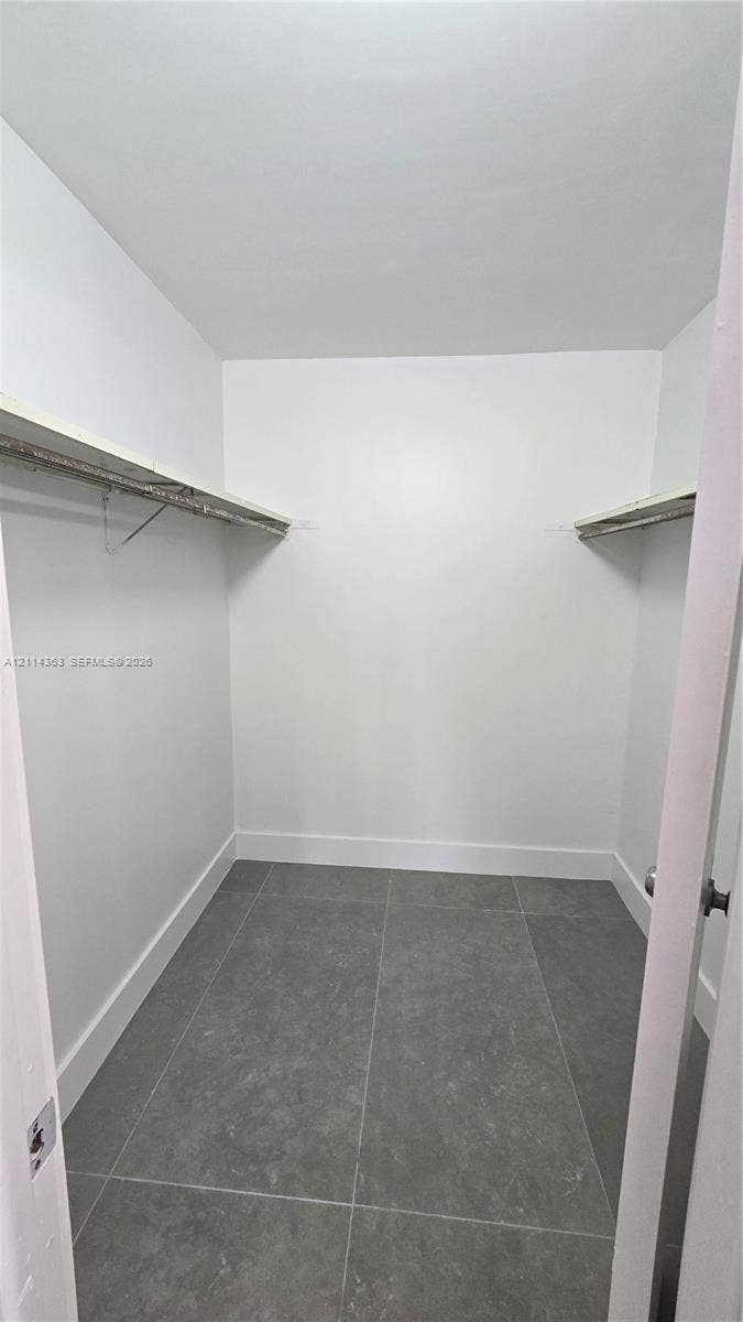 14840 Naranja Lakes Boulevard, #1G, Homestead, FL 33032 Walk-in closet featuring grey stone-finish tile flooring and dual overhead shelving with integrated clothing rods