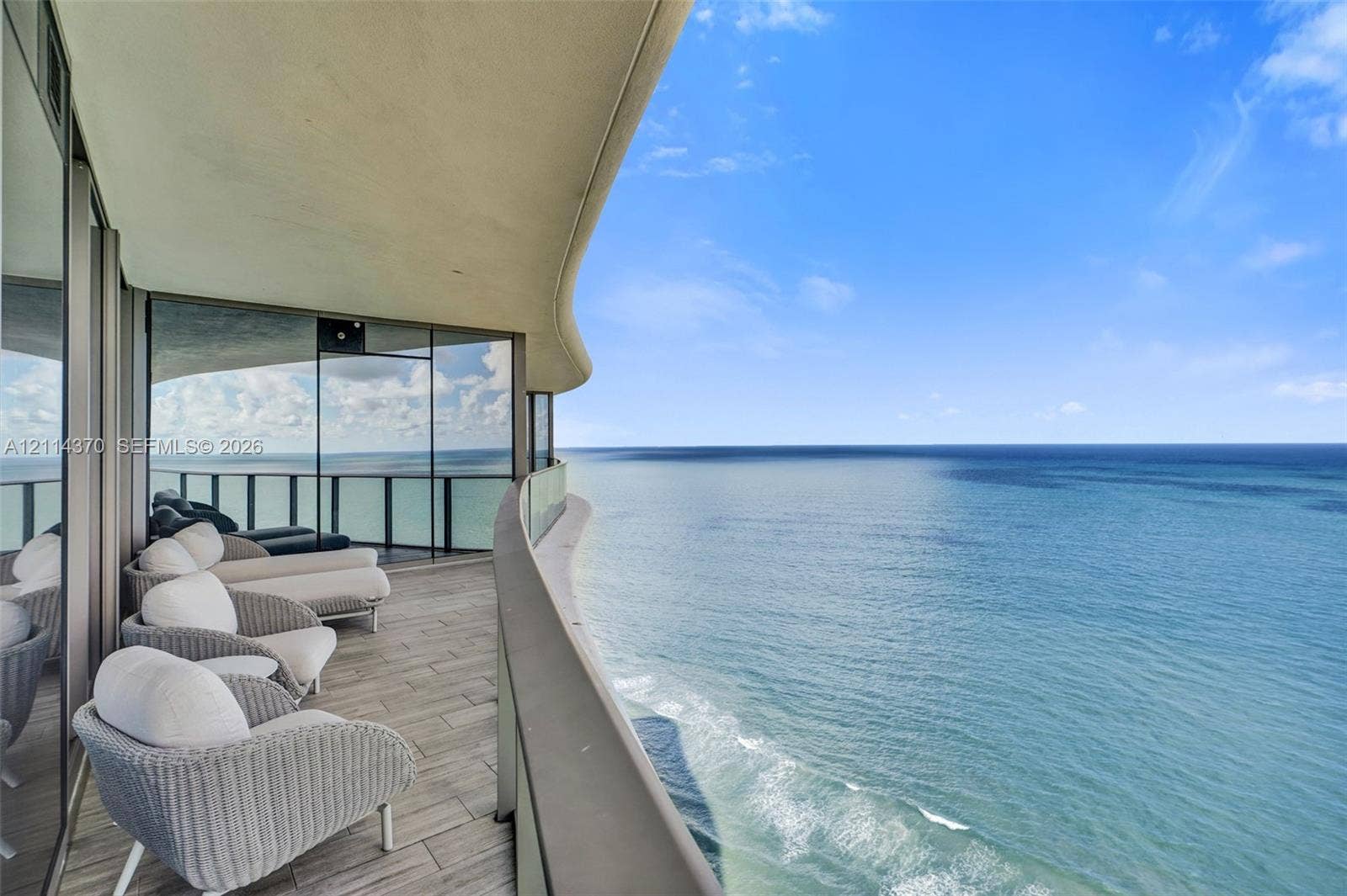 Sunny Isles Beach, Sunny Isles Beach, FL 33160 Curved balcony featuring wood-finish tile flooring, floor-to-ceiling glass paneling, and a glass balustrade overlooking the ocean