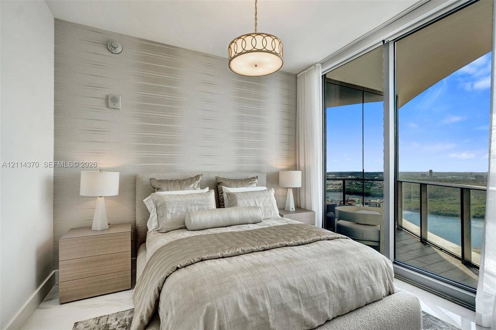Sunny Isles Beach, Sunny Isles Beach, FL 33160 Floor-to-ceiling glass sliding doors, private balcony, textured accent wall, polished stone flooring, and drum pendant lighting