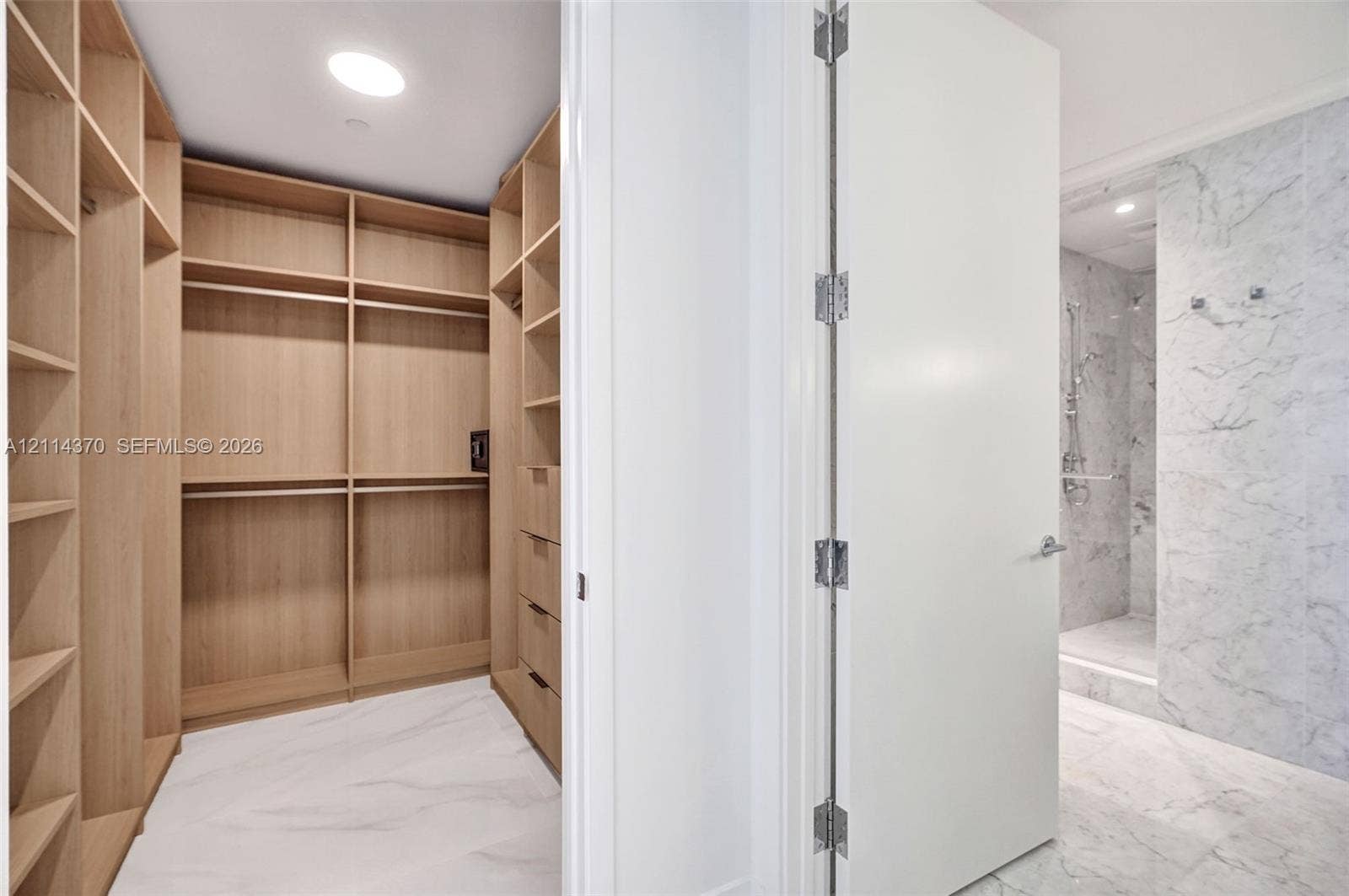 Sunny Isles Beach, Sunny Isles Beach, FL 33160 Custom wood-finish shelving and cabinetry, stone-pattern flooring, and a walk-in shower featuring floor-to-ceiling stone-pattern tile