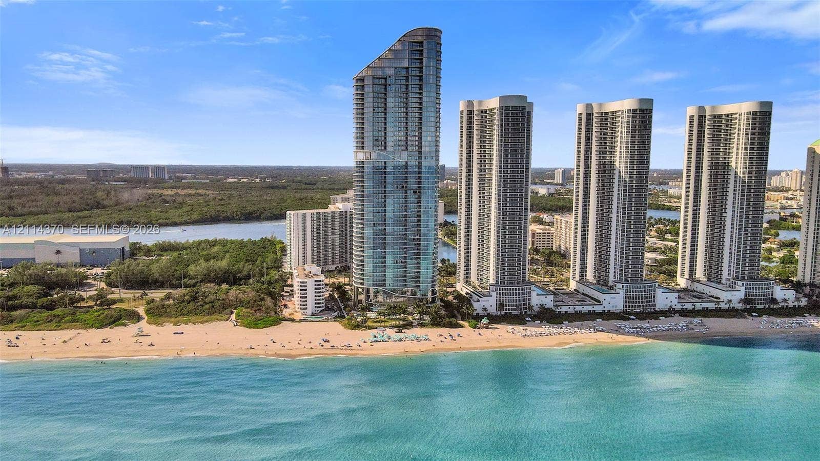 Sunny Isles Beach, Sunny Isles Beach, FL 33160 High-rise tower featuring glass-paneled exterior walls and direct oceanfront access to a sandy beach