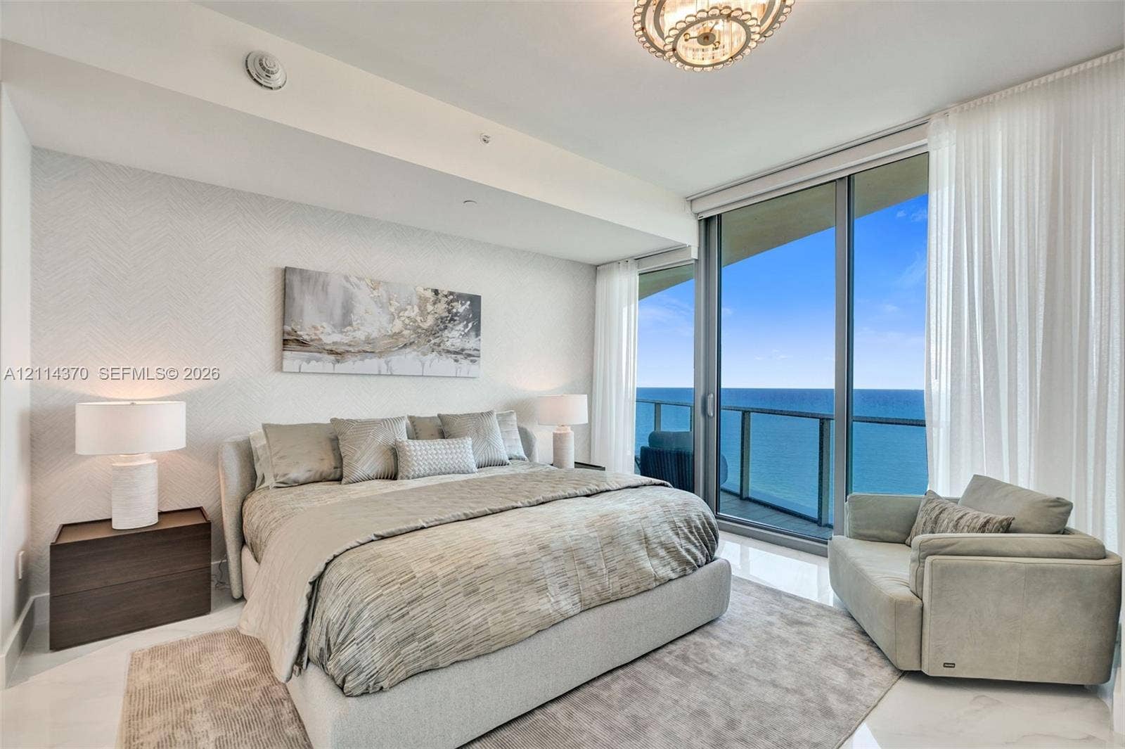 Sunny Isles Beach, Sunny Isles Beach, FL 33160 Floor-to-ceiling glass sliding doors, private balcony, polished stone flooring, textured wall covering, and a modern circular chandelier