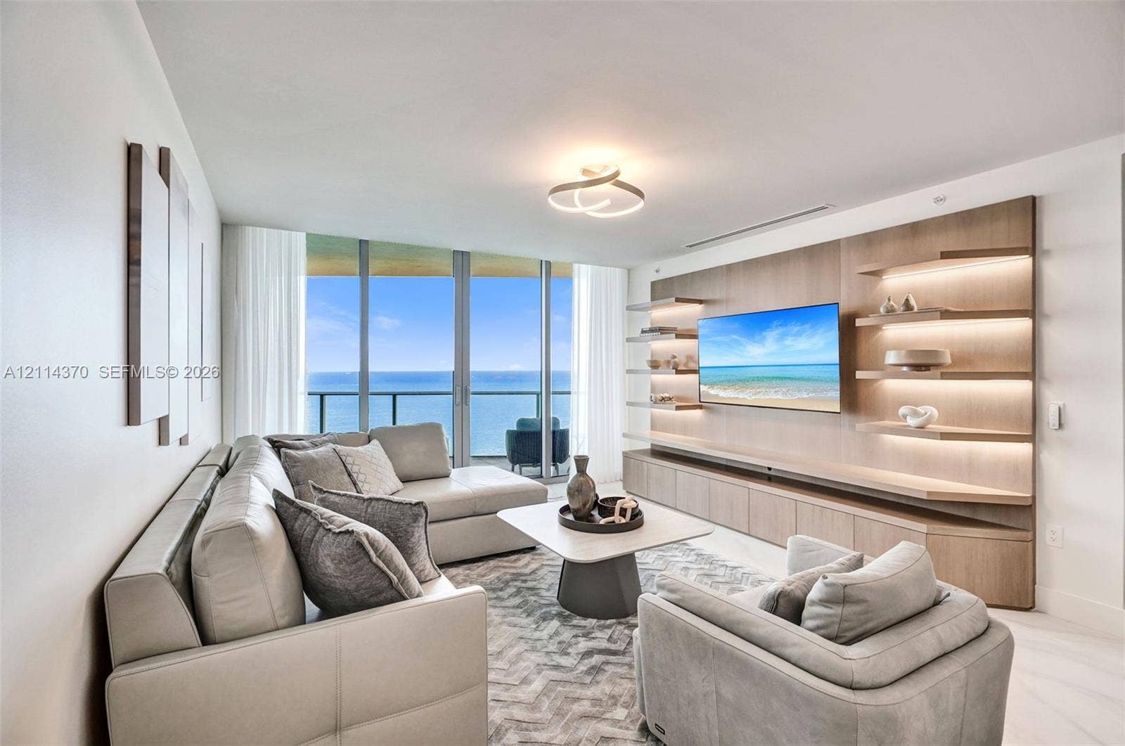 Sunny Isles Beach, Sunny Isles Beach, FL 33160 Floor-to-ceiling glass windows, custom built-in wood cabinetry with integrated accent lighting, floating display shelving, and light-tone flooring