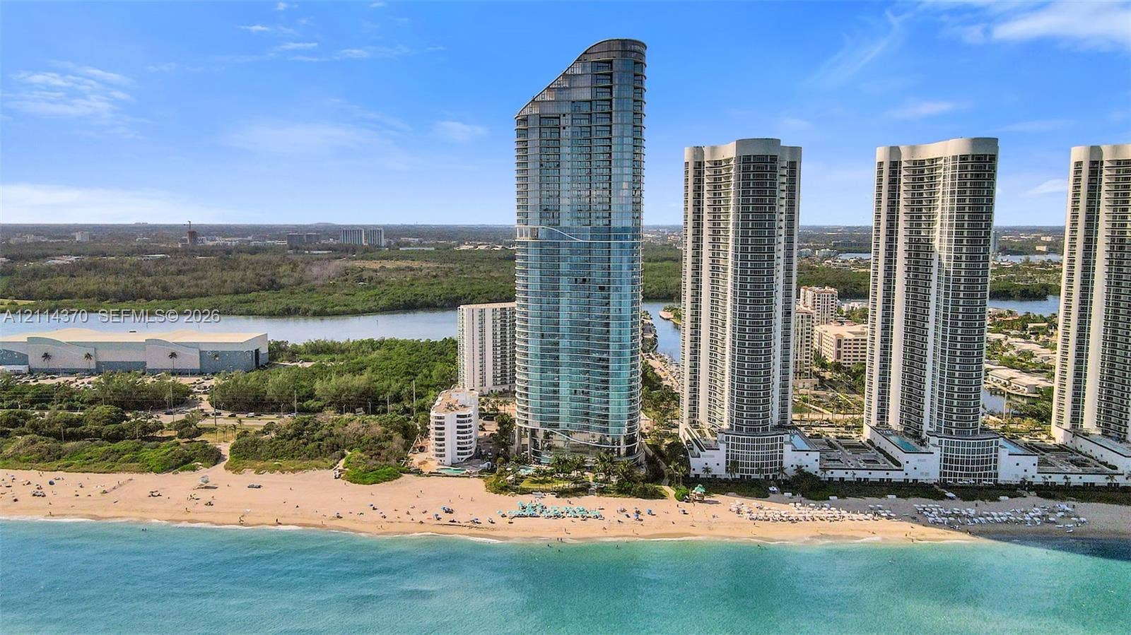 Sunny Isles Beach, Sunny Isles Beach, FL 33160 High-rise residential tower featuring floor-to-ceiling glass paneling, tiered architectural design, and direct beachfront positioning