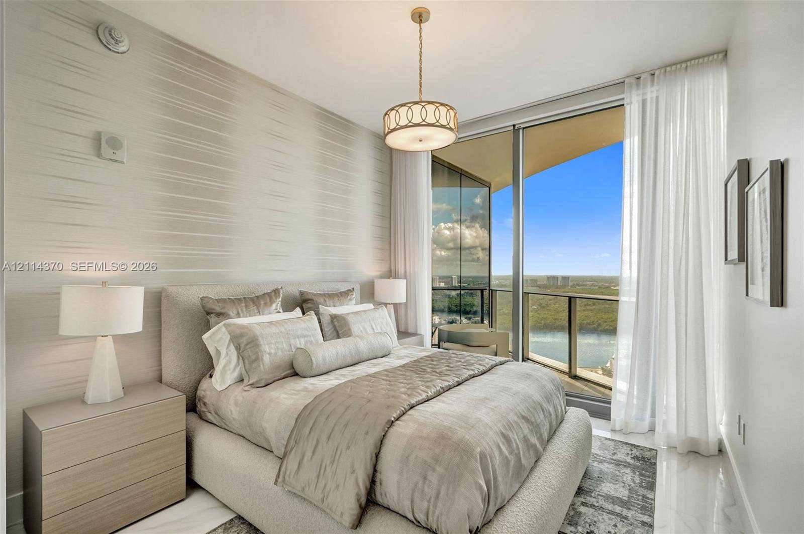 Sunny Isles Beach, Sunny Isles Beach, FL 33160 Floor-to-ceiling glass paneling, polished stone flooring, textured wall covering, and a contemporary drum pendant light fixture, with access to a private balcony