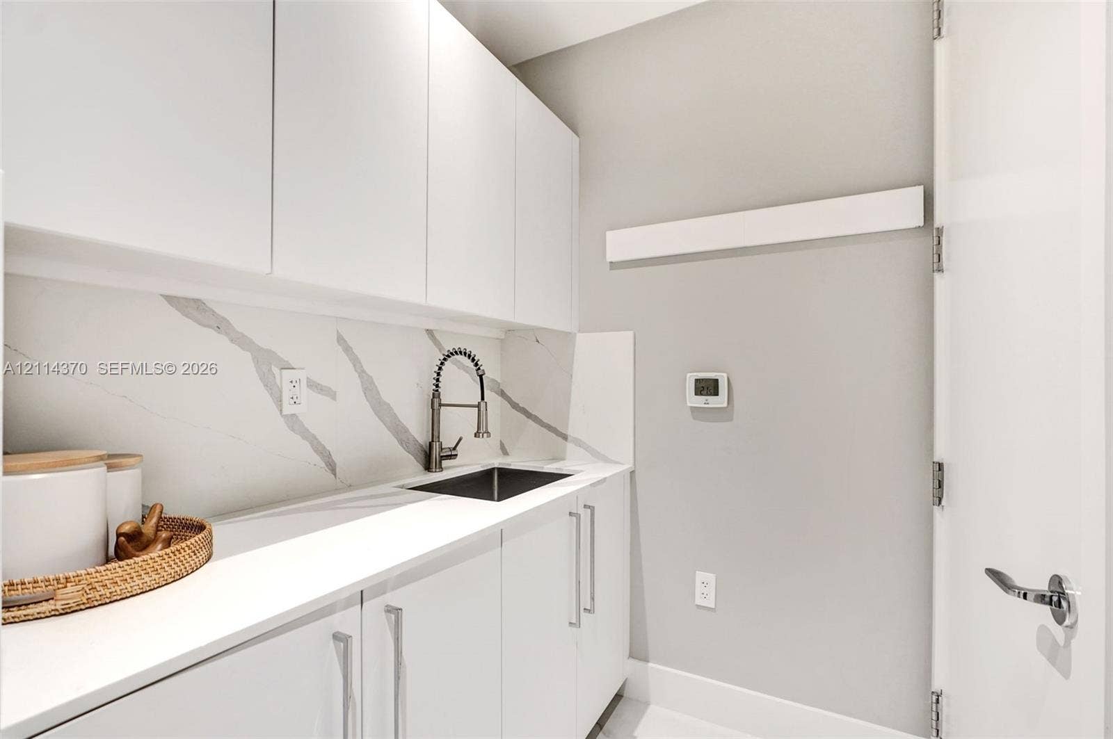 Sunny Isles Beach, Sunny Isles Beach, FL 33160 Minimalist cabinetry with polished hardware, stone-patterned backsplash, undermount sink featuring a high-arc pull-down faucet, and solid-surface countertop