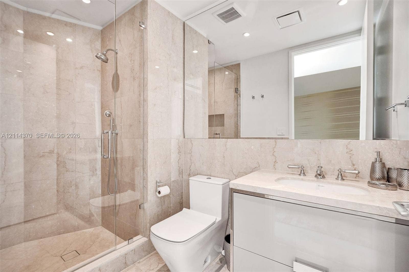 Sunny Isles Beach, Sunny Isles Beach, FL 33160 Full-height stone wall tiling, glass-enclosed shower, stone vanity countertop with integrated sink, and wall-to-wall mirror