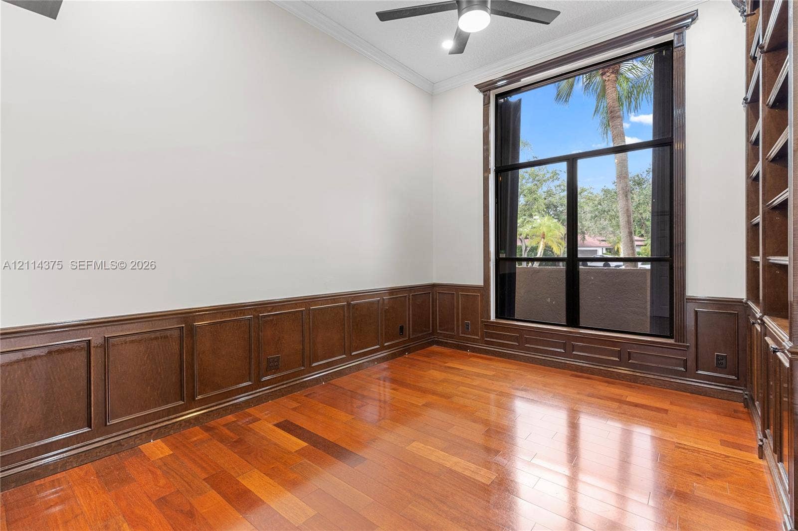 1206 S Manor Drive S, Weston, Weston, FL 33326 Wood-finish flooring, custom dark wood wall paneling, full-height built-in shelving, floor-to-ceiling windows, and crown molding