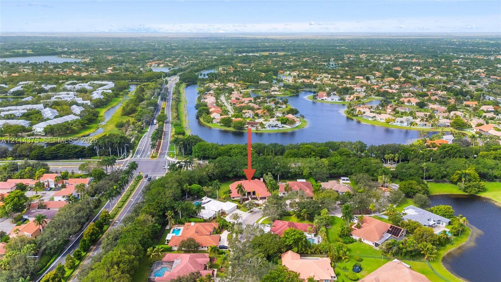 1206 S Manor Drive S, Weston, Weston, FL 33326 Aerial perspective of a multi-level residence featuring a clay tile roof, paved driveway, expansive lot with mature landscaping, and proximity to multiple water features