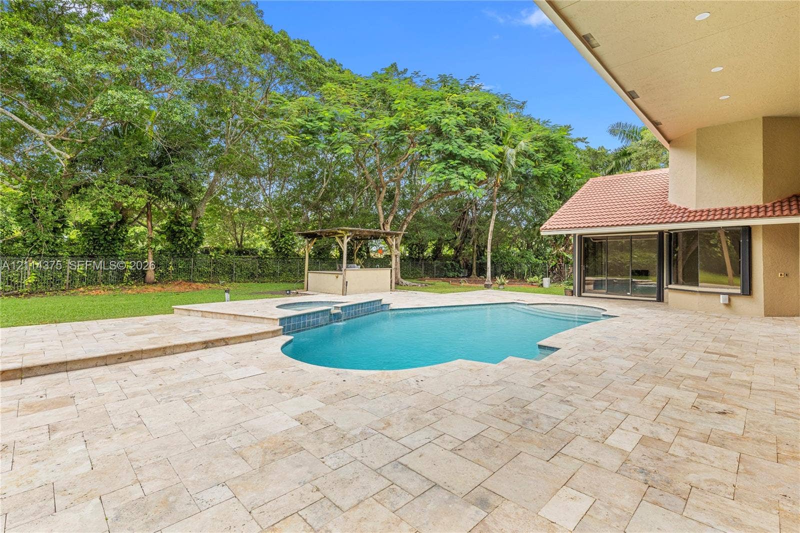 1206 S Manor Drive S, Weston, Weston, FL 33326 Extensive stone-paver patio featuring a swimming pool with an integrated spa, built-in outdoor kitchen structure, and manicured lawn