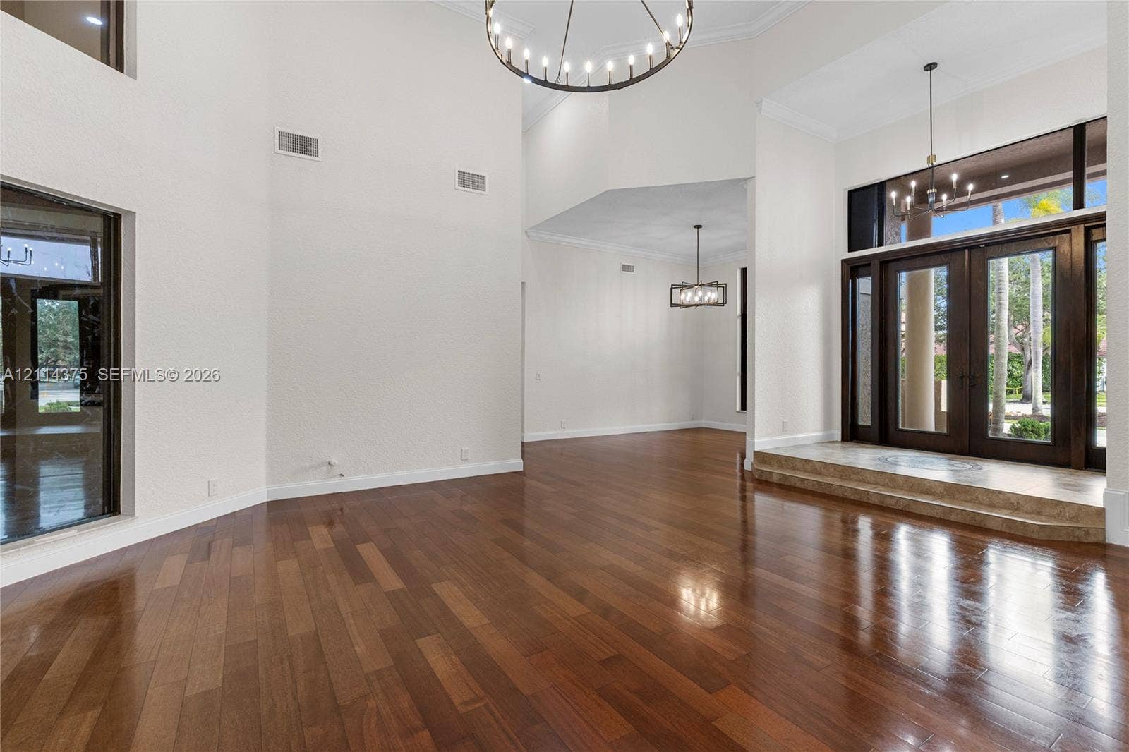 1206 S Manor Drive S, Weston, Weston, FL 33326 Grand foyer featuring high ceilings, wood-finish flooring, double-door entry, a circular chandelier, and a stone-tiled platform