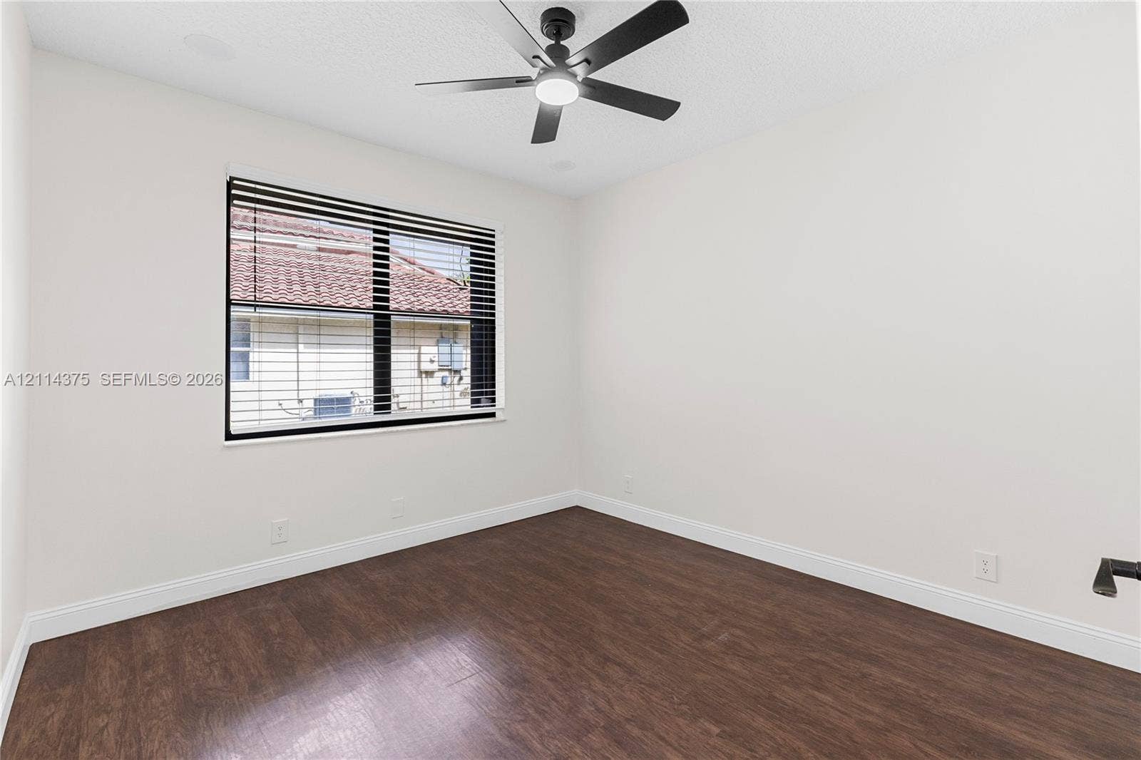 1206 S Manor Drive S, Weston, Weston, FL 33326 Interior room featuring dark-tone wood-finish flooring, a contemporary matte black ceiling fan with an integrated light, and a single window with horizontal blinds