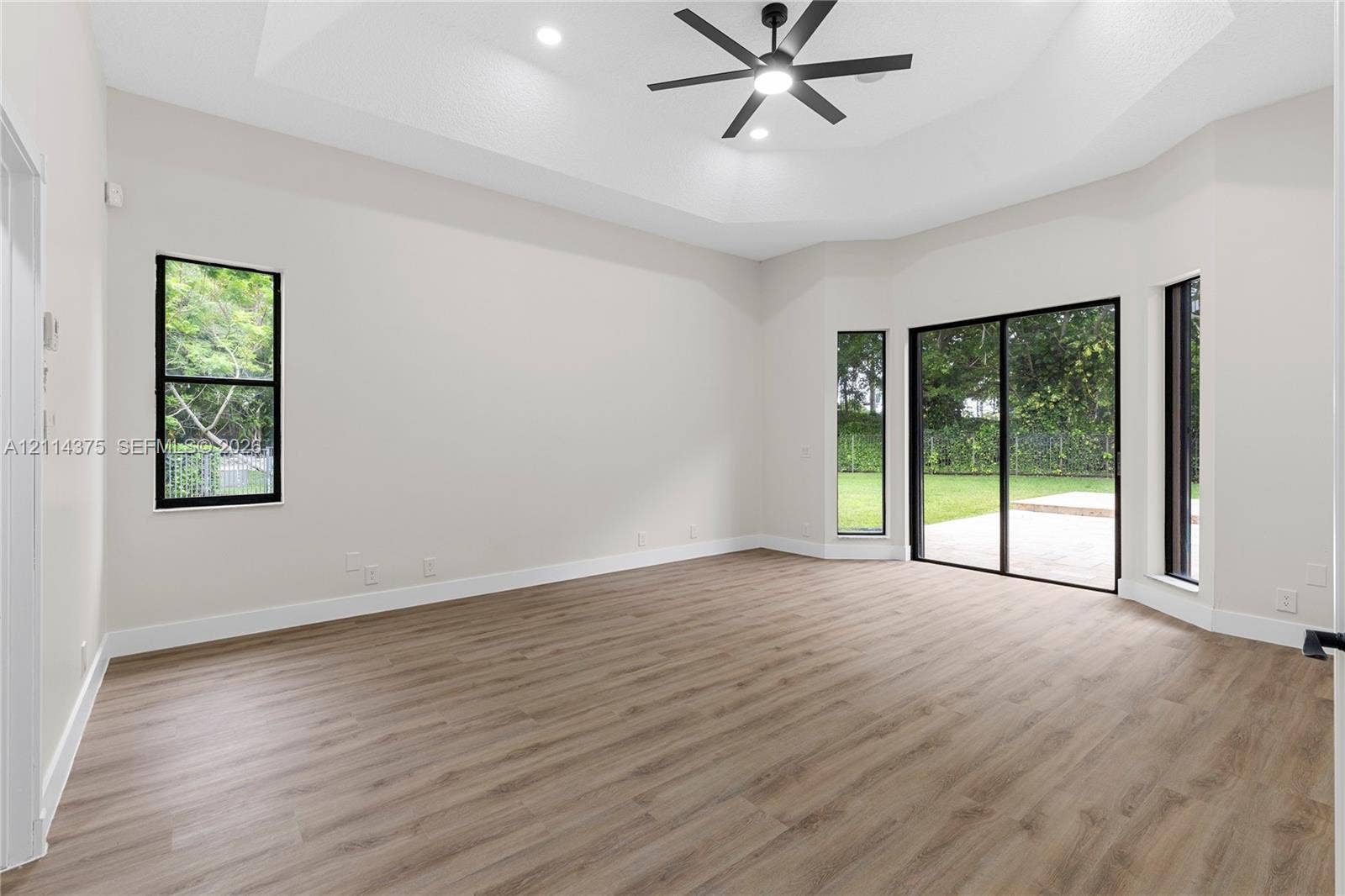 1206 S Manor Drive S, Weston, Weston, FL 33326 Tray ceiling with integrated recessed lighting, wood-finish flooring, black-framed windows, and sliding glass doors with exterior access