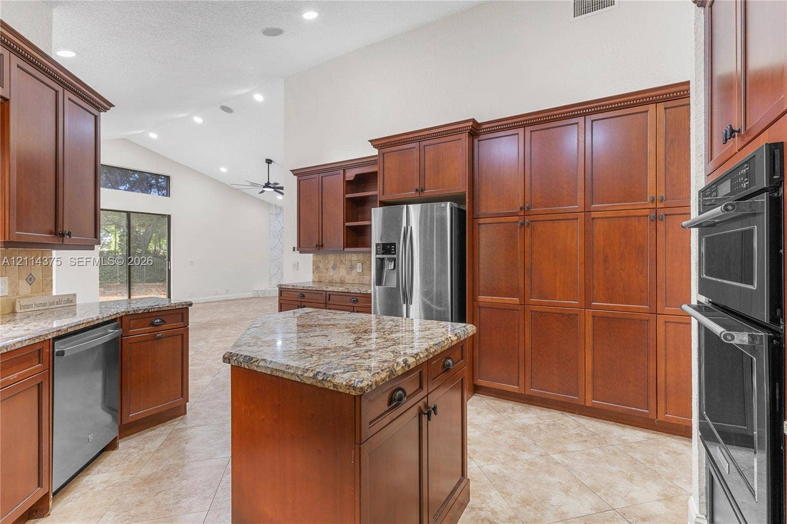 1206 S Manor Drive S, Weston, Weston, FL 33326 Kitchen featuring full-height stained wood cabinetry, stone countertops, central island, double wall oven, and tile flooring under a vaulted ceiling