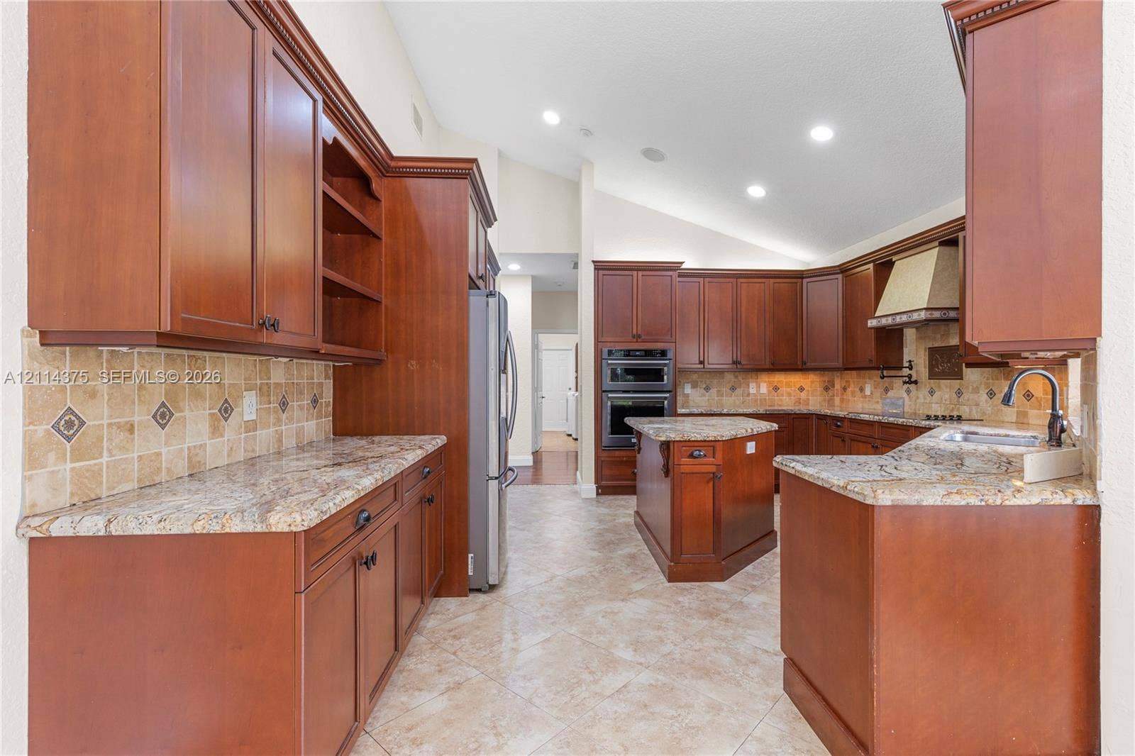 1206 S Manor Drive S, Weston, Weston, FL 33326 Kitchen featuring cherry-finish cabinetry, stone countertops, square-tile backsplash with decorative inserts, double wall oven, and center island