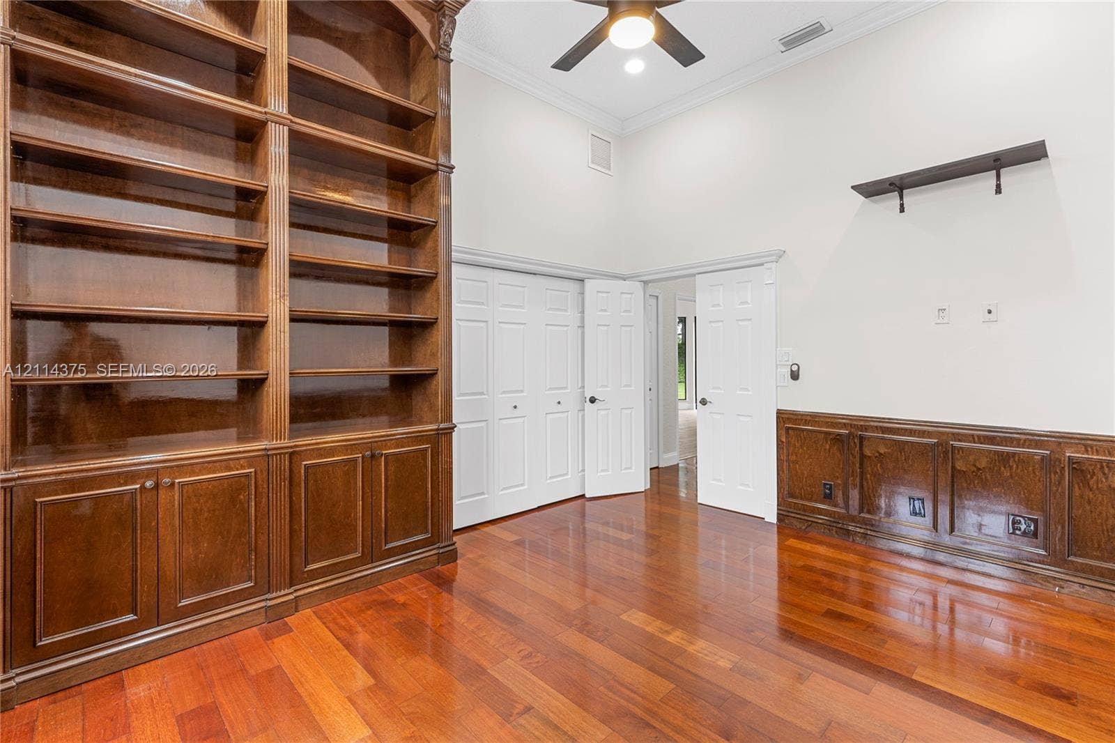 1206 S Manor Drive S, Weston, Weston, FL 33326 High-ceiling room featuring built-in floor-to-ceiling wood shelving, stained wood wainscoting, wood-finish flooring, and crown molding