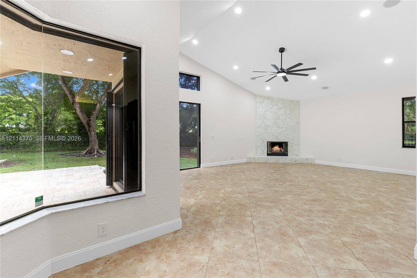 1206 S Manor Drive S, Weston, Weston, FL 33326 Spacious interior featuring tile flooring, vaulted ceilings with recessed lighting, a stone-surround fireplace, and large bay windows