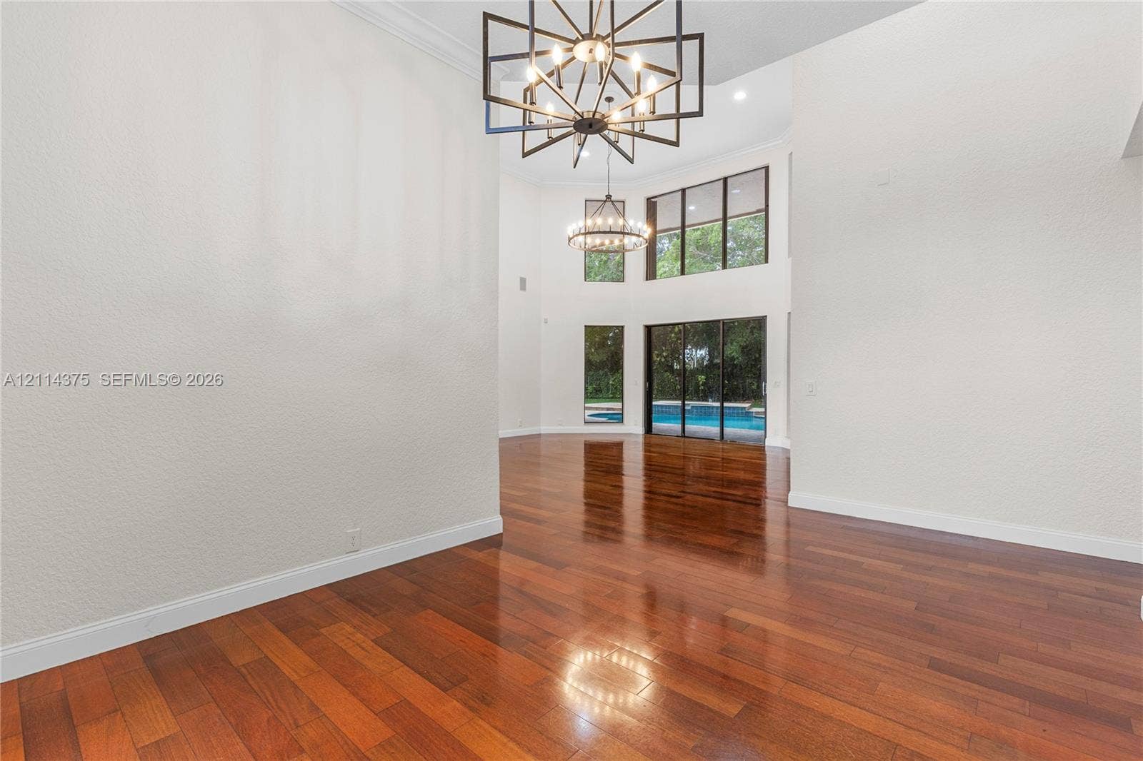 1206 S Manor Drive S, Weston, Weston, FL 33326 Two-story interior space featuring wood-finish flooring, high ceilings, geometric metal chandeliers, and oversized windows