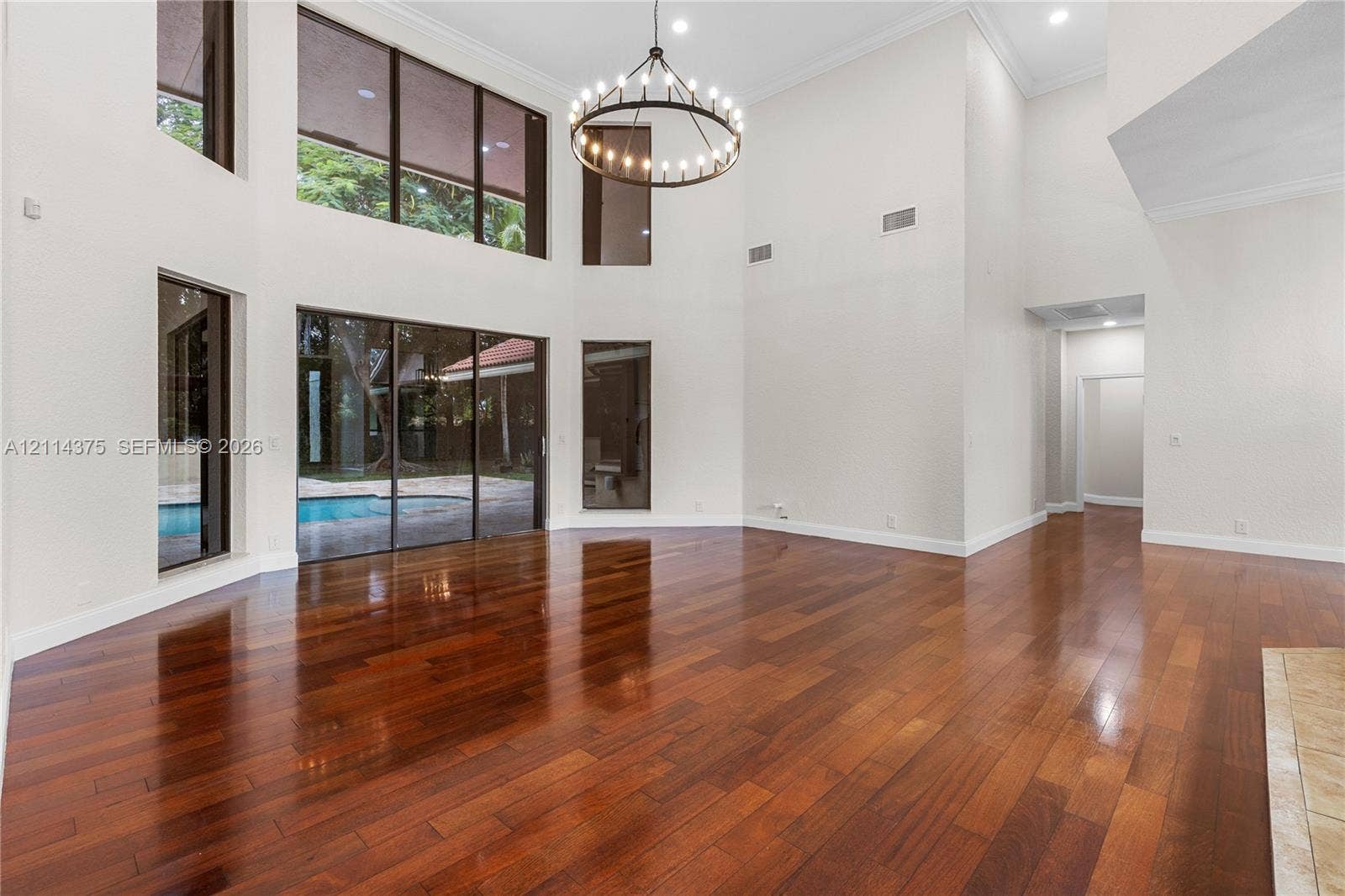 1206 S Manor Drive S, Weston, Weston, FL 33326 Double-height ceilings featuring floor-to-ceiling windows, wood-finish flooring, a large circular iron chandelier, and recessed lighting