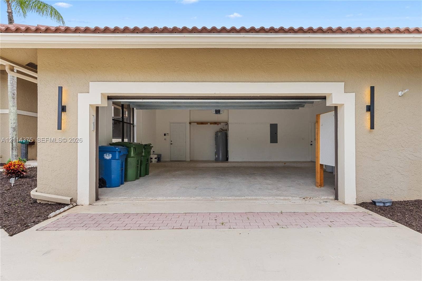 1206 S Manor Drive S, Weston, Weston, FL 33326 Stucco exterior garage featuring decorative trim, integrated wall-mounted lighting, and a concrete driveway with a paver accent strip