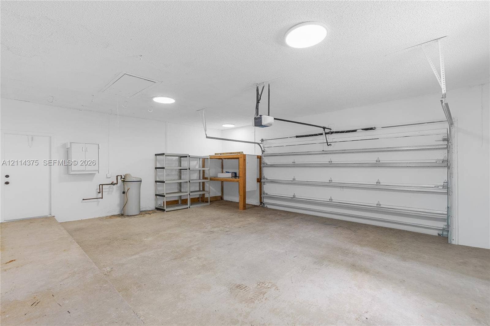 1206 S Manor Drive S, Weston, Weston, FL 33326 Multi-car garage featuring a concrete floor, automated sectional door, and flush-mount ceiling lighting