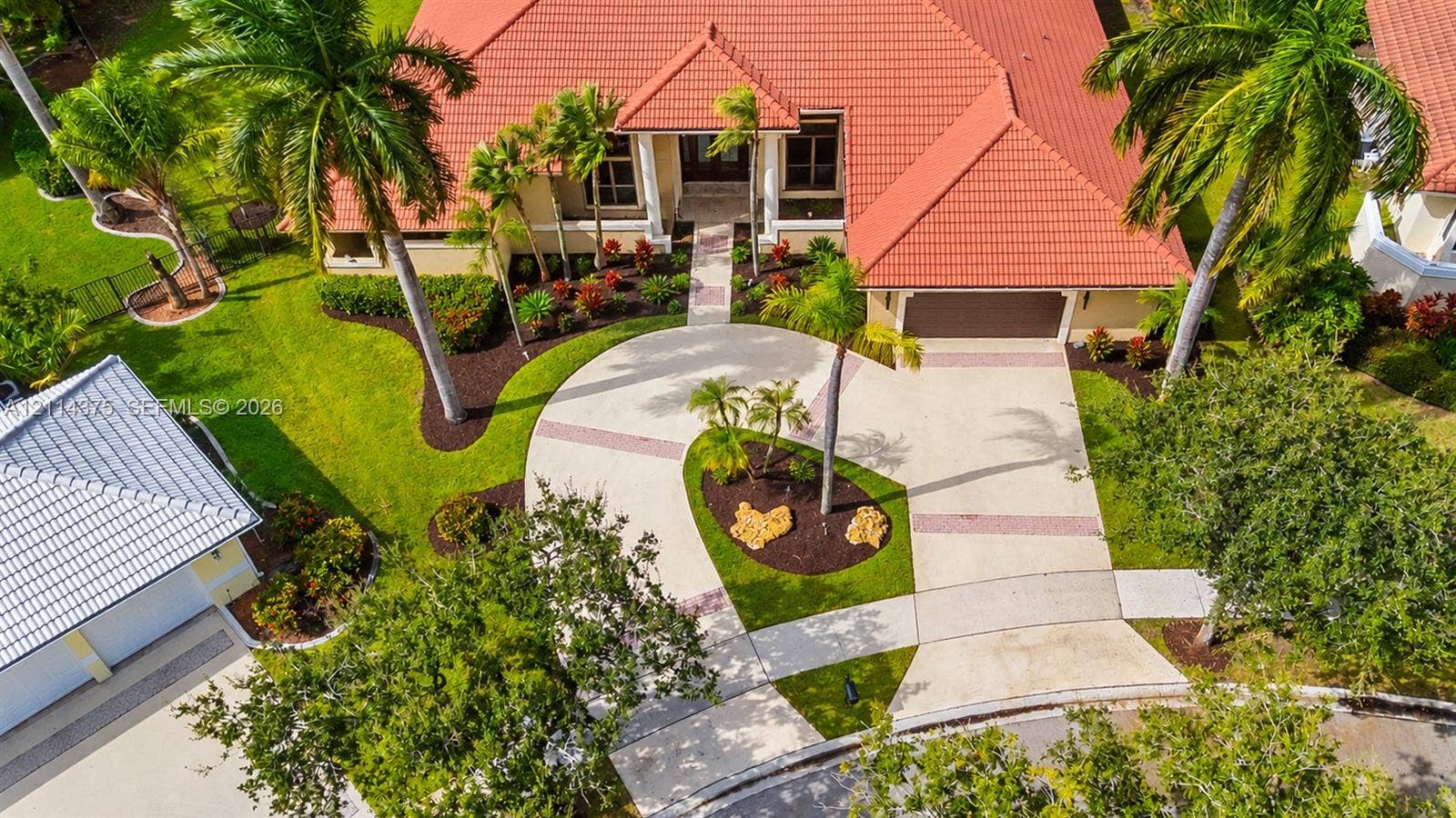 1206 S Manor Drive S, Weston, Weston, FL 33326 Exterior featuring a tile roof, circular driveway, multi-car garage, manicured landscaping, and mature palm trees